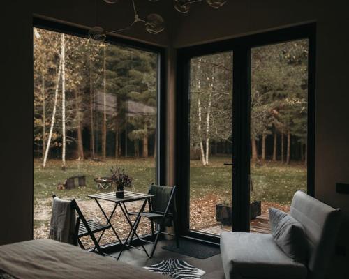 a room with a bed and a table and a window at Briežu Stacija Off Grid Cabin in Līgatne