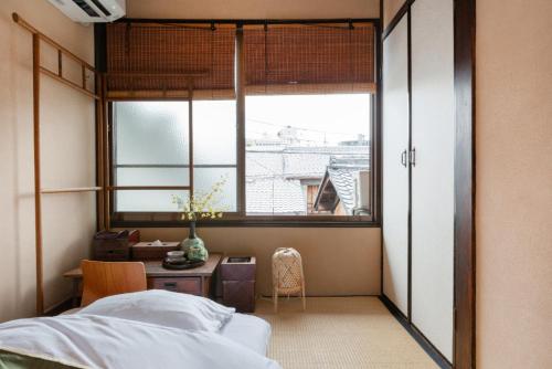 a bedroom with a bed and a table and a window at お宿梅夜Guesthouse Umeya in Kyoto