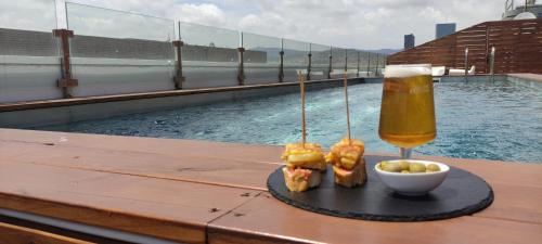 a drink and food on a table next to a swimming pool at Eurohotel Diagonal Port in Barcelona