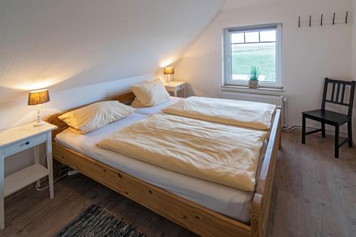 a bedroom with a bed and a desk and a window at Deichhaus in Neßmersiel