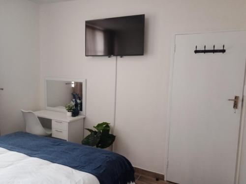 ein Schlafzimmer mit einem Bett und einem TV an der Wand in der Unterkunft Private Room Chez Khanyi Homestays in Pretoria