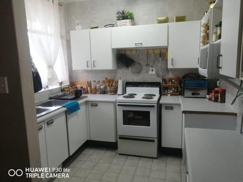 a kitchen with white cabinets and a stove top oven at Private Room Chez Khanyi Homestays in Pretoria