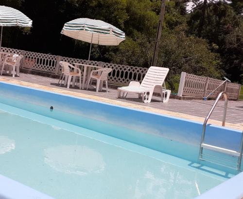 una piscina con sillas, una mesa y una sombrilla en Pousada Pedacinho do Céu -Chalé Familia, en Cunha