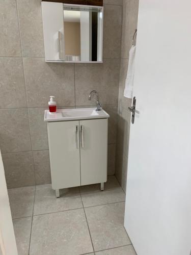 een badkamer met een witte wastafel en een spiegel bij Apto e Suítes Praia do Itapocoroi in Penha