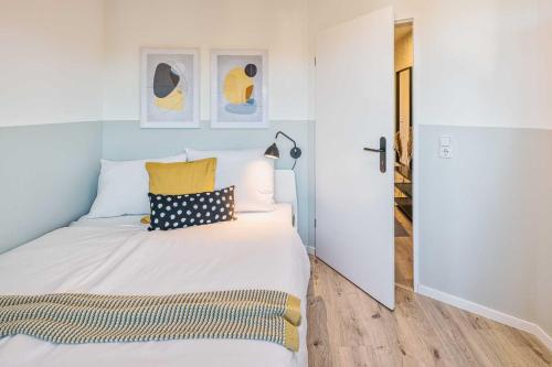 - une chambre avec un lit blanc et des oreillers jaunes dans l'établissement new apartment I cozy I Netflix I WLAN I near airport, à Dresde