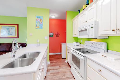 a kitchen with white appliances and green and red walls at Plum Cute by Meyer Vacation Rentals in Gulf Shores