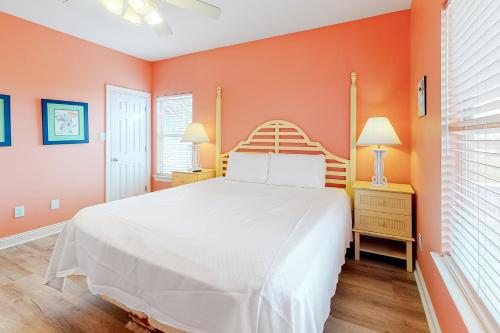 a bedroom with a white bed and orange walls at Plum Cute by Meyer Vacation Rentals in Gulf Shores