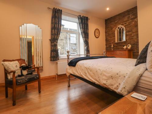 a bedroom with a bed and a chair and a window at Heather Corner in Keighley