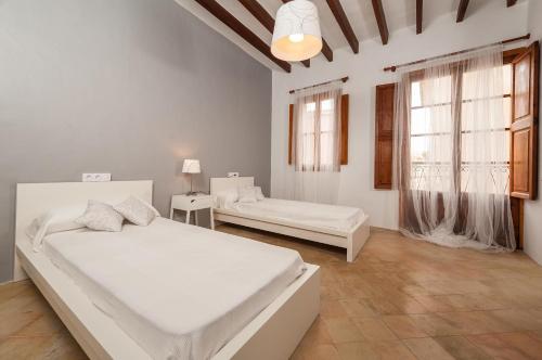 a white bedroom with two beds and a window at Holiday Home Ca Na Blan ca in Alcudia