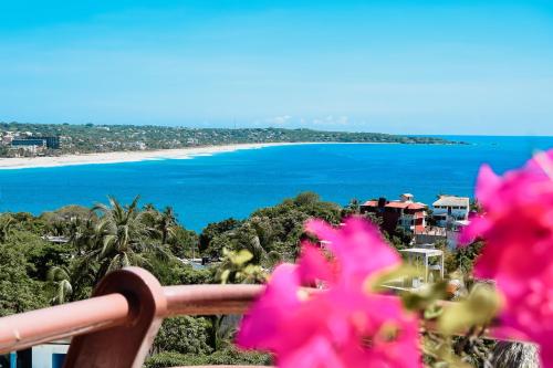 a view of the beach from a balcony with pink flowers at Hotel El Mirador in Puerto Escondido