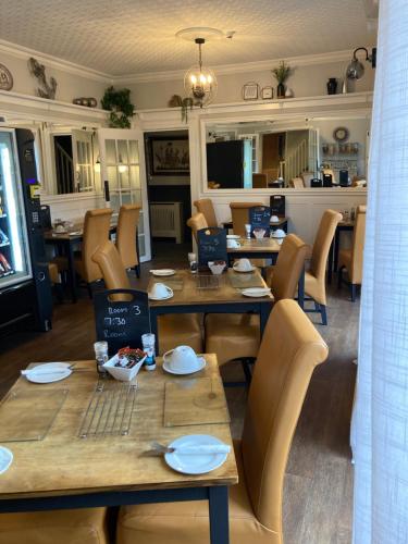 a restaurant with wooden tables and chairs and a dining room at Abbey Court Guest House in Carlisle