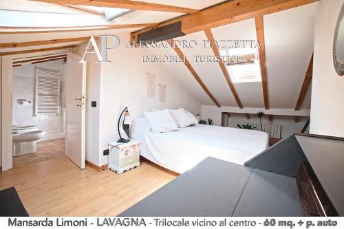 1 dormitorio con cama blanca y baño en Mansarda Limoni, en Lavagna