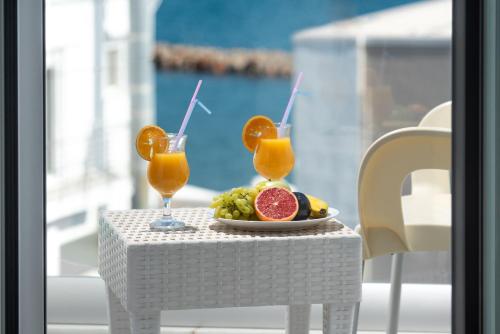 un tavolo con un piatto di frutta e due bicchieri di succo d'arancia di Coral Hotel a Ierápetra