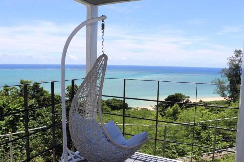 - un fauteuil roulant sur un balcon donnant sur l'océan dans l'établissement GLORY ISLAND OKINAWA Yabusachi Resort, à Nanjō