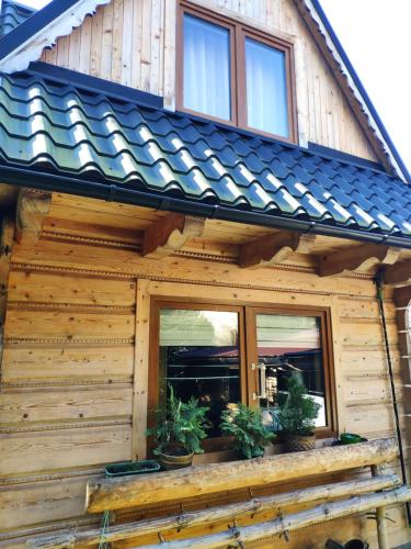 una cabaña de madera con macetas en el porche en Marynka, en Zakopane