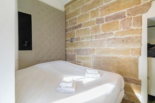 - une chambre avec un mur en briques et un lit avec des serviettes dans l'établissement Le Saint B au pied de la Cathédrale saint Bénigne, à Dijon
