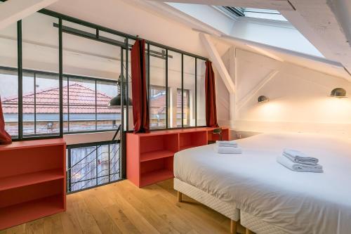 a bedroom with a large bed and large windows at L'ATELIER DU CHAPEAU ROUGE EN PLEIN CENTRE VILLE in Dijon