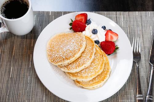 een bord met pannenkoeken en aardbeien en een kopje koffie bij Holiday Inn & Suites Philadelphia W - Drexel Hill, an IHG Hotel in Drexel Hill