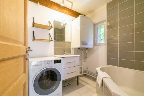 une salle de bain avec un lave-linge et une baignoire dans l'établissement LE ROUSSEAU charme et authenticité- SRloc, à Dijon