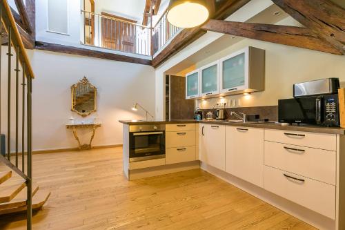 une cuisine avec des armoires blanches et un plancher en bois dans l'établissement Le Mucie*****LOFT au centre ville de Dijon, à Dijon