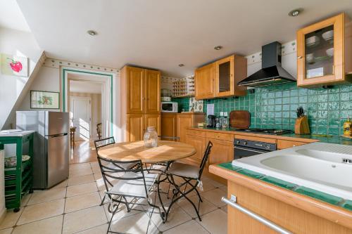 une cuisine avec une table, des chaises et un réfrigérateur dans l'établissement Le panoramique, au centre historique de Dijon, à Dijon