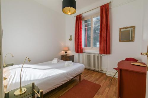 a bedroom with a bed and a window with red curtains at Le Chaussier, en plein centre ville de Dijon in Dijon