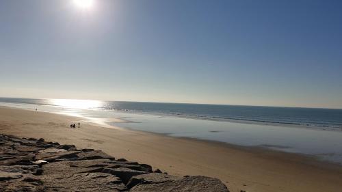 two people walking on a beach with the ocean at Sylvie propriétaire du mobil-home in Saint-Pair-sur-Mer