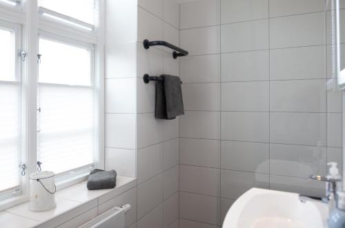 a white tiled bathroom with a sink and a window at Stadthaus Jürgensby in Flensburg