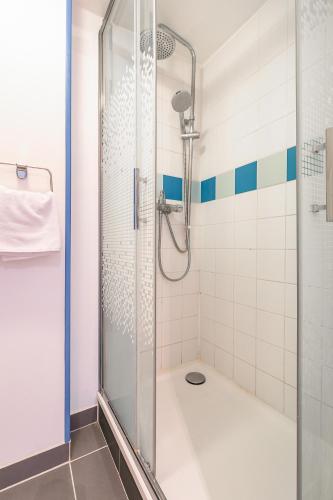 une douche avec une porte vitrée dans une salle de bain dans l'établissement Le Godrans, en plein centre ville de Dijon, à Dijon