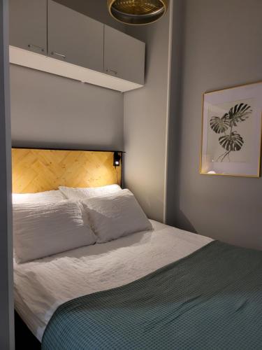 a bedroom with a white bed with a wooden headboard at Studio 7 - Air-conditioned, P-spot & Self Check-in in Jyväskylä