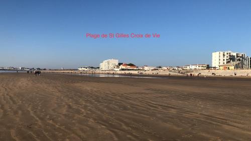 a sandy beach with buildings in the background at L Atypique in LʼÎle-dʼOlonne