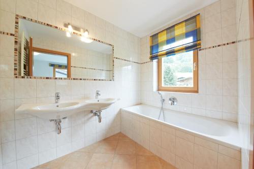 a bathroom with a sink and a tub and a mirror at Appartement Mitteregg in Saalbach Hinterglemm