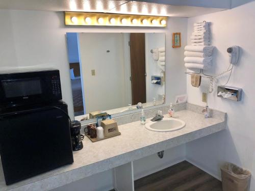 a bathroom with a sink and a large mirror at Budget Host Inn in Ironwood