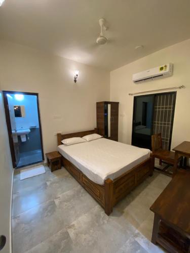 a bedroom with a bed and a desk and a window at Erisha Tadoba in Mohurli