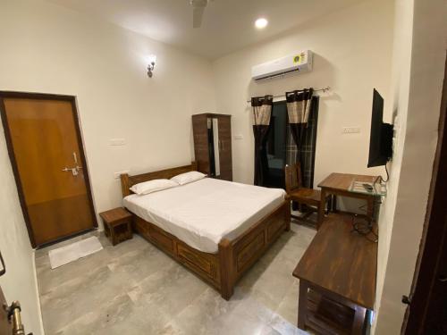 a bedroom with a bed and a desk and a television at Erisha Tadoba in Mohurli