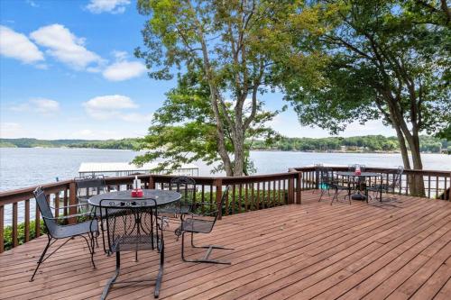 a wooden deck with two tables and chairs on the water at Private Dock Spacious Lakefront Home in Stover in Laurie