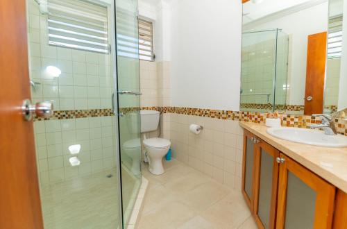 a bathroom with a toilet and a glass shower at Adulo Apartments in Bridgetown