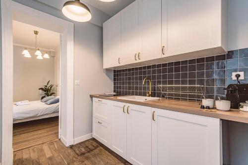 a kitchen with white cabinets and a bed in a bedroom at Roi soleil, face à la Cathédrale - 2G in Reims