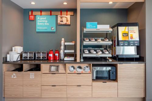 a coffee shop with a counter with a microwave at avid hotels Milwaukee West - Waukesha by IHG in Pewaukee
