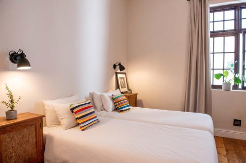 a bedroom with two beds with white sheets and a window at Villa Viva Cape Town in Cape Town