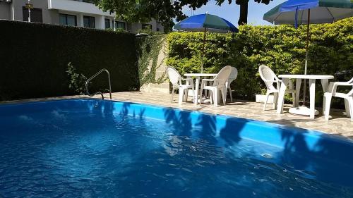 una piscina con sillas, mesas y sombrillas en Dell Osky Pousada en Florianópolis