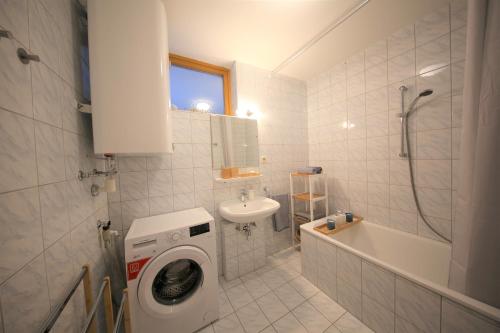 een badkamer met een wasmachine en een wastafel bij Ganze Wohnung am Wörthersee in Pörtschach am Wörthersee
