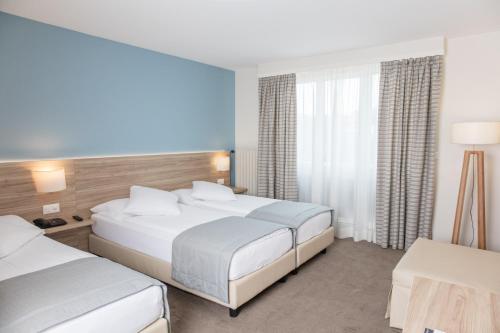 una camera d'albergo con due letti e una finestra di Hôtel de Chailly a Montreux
