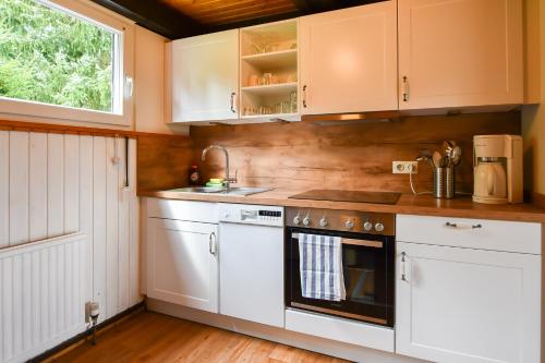 a kitchen with white cabinets and a stove at Eulenhäusle in Schramberg