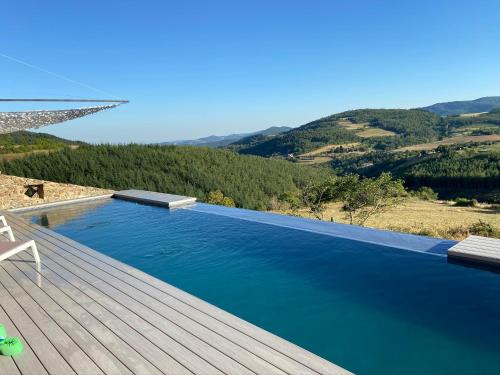 a swimming pool with a wooden deck and the water at CASARIOU Les Bernards Villa Grande bâtisse 12p avec cheminée bain nordique billiard piscine in Vaudevant