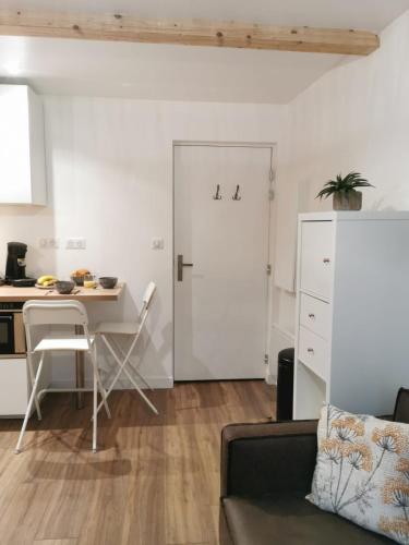 a living room with a table and a white door at Les appartements du centre, refaits à neuf, climatisés, hyper centre, 50m à pieds des commerces, restaurants, parking gratuit in Salies-de-Béarn