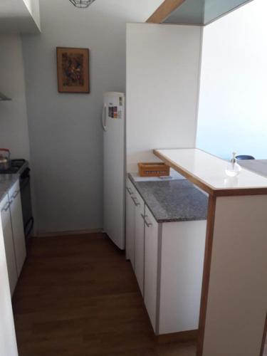 een keuken met witte werkbladen en een witte koelkast bij Departamento de Barrio Belgrano in Bariloche