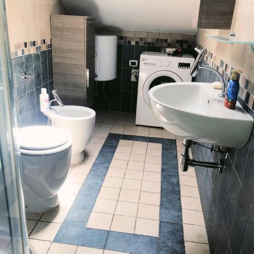 a bathroom with a toilet and a sink and a washing machine at Appartamento L’Angelica in Assemini