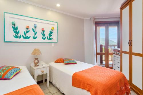 a bedroom with two beds and a balcony at Vista Panorâmica do Mar - Praia Grande, Ubatuba SP in Ubatuba