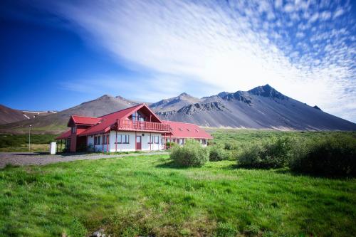 a house in a field with mountains in the background at Hotel Hafnarfjall in Borgarnes